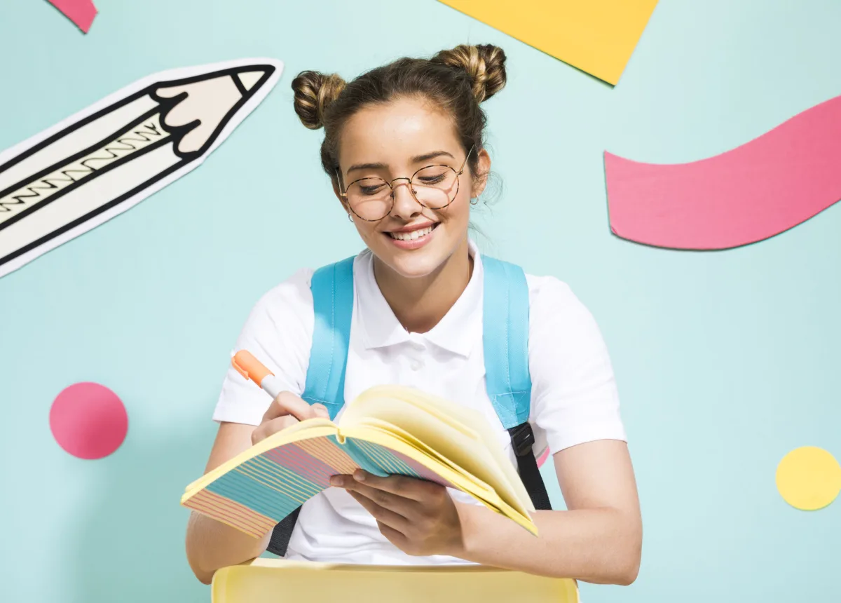 A student smiling while writing in a notebook